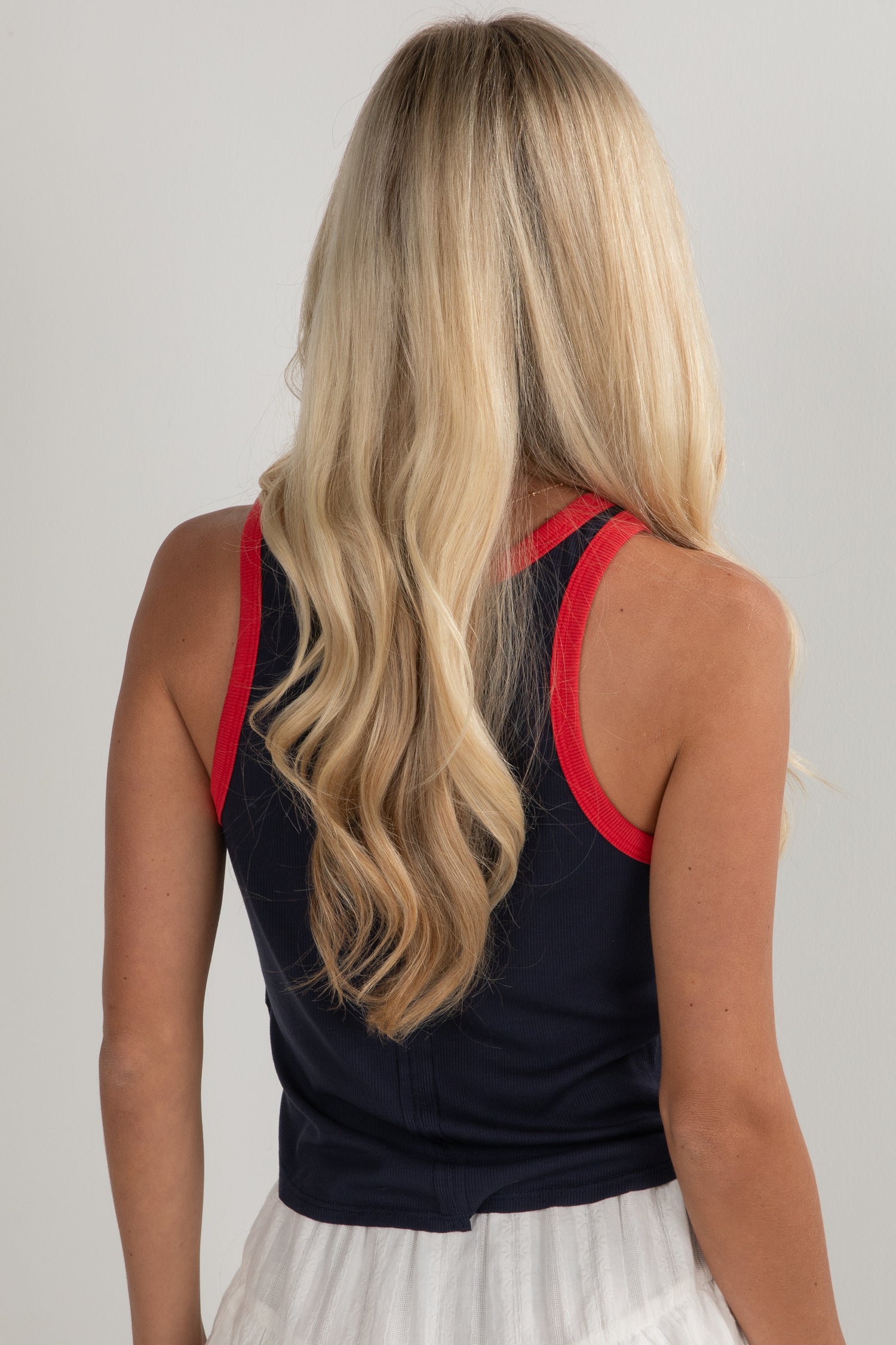 Person wearing a black sleeveless top with red trim on a plain background