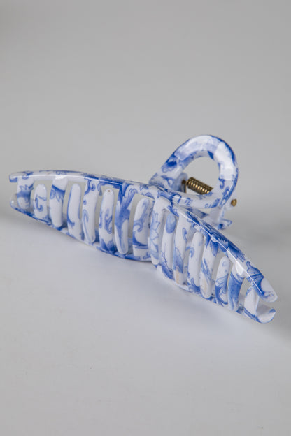 Blue and white marbled hair clip on a gray background