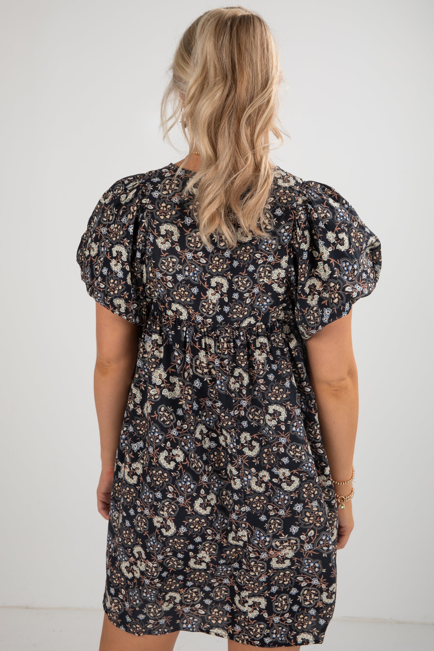 Woman wearing a floral dress with puff sleeves against a white background