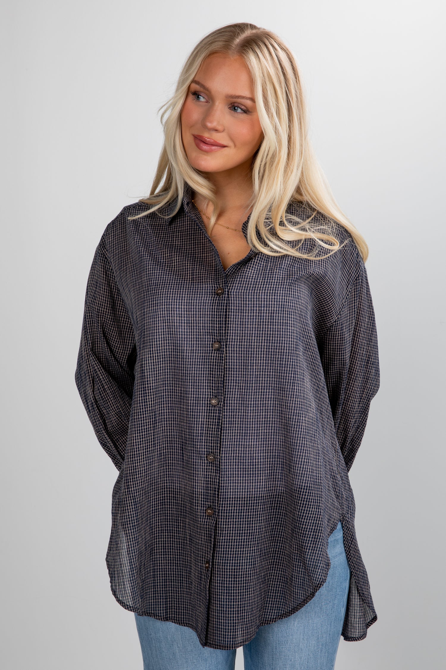 Woman wearing a dark checkered shirt against a plain background