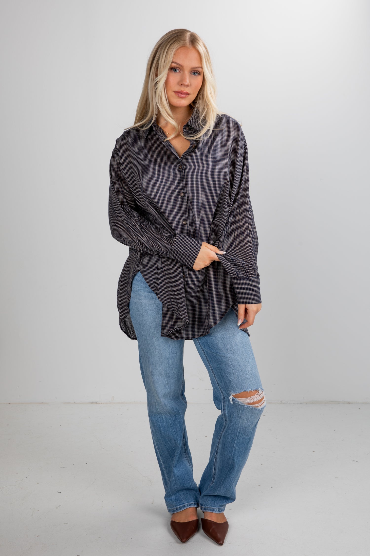 Woman wearing a dark gray oversized shirt and blue jeans on a white background