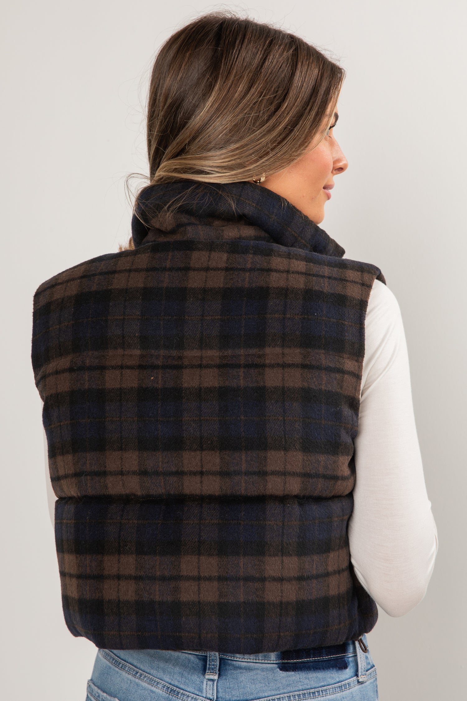 Person wearing a plaid puffer vest on a plain background