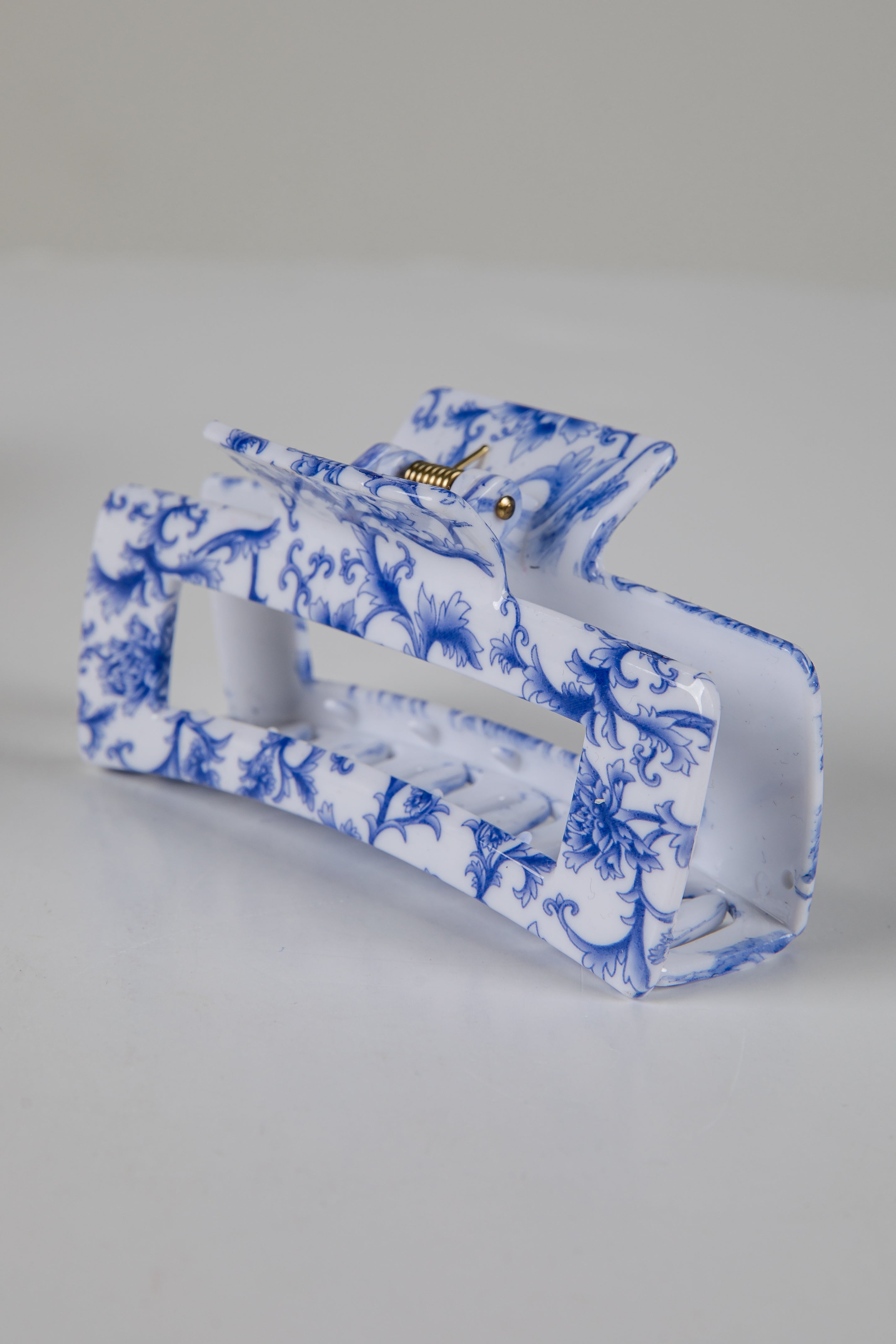 Blue and white floral patterned clutch bag on a gray background
