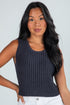 Woman wearing a dark ribbed tank top against a plain background