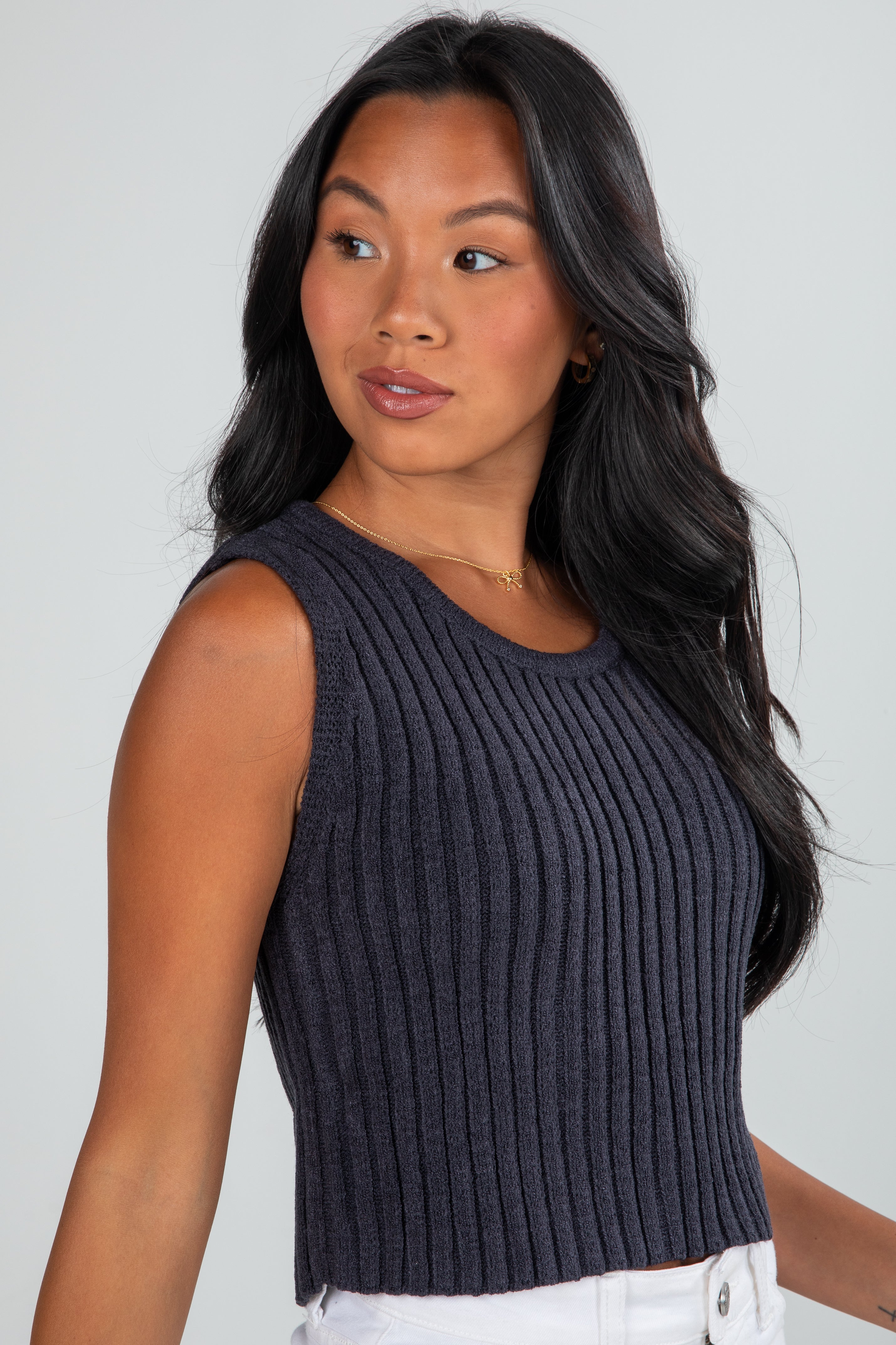Woman wearing a dark gray ribbed tank top against a plain background