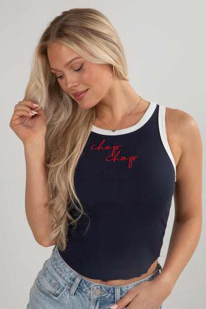 Woman wearing a navy tank top with red text on a plain background