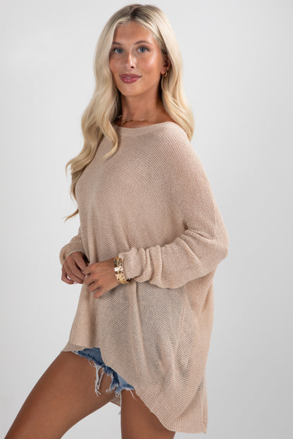 Woman wearing a beige sweater and denim shorts on a white background
