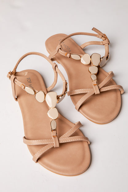 Pair of tan sandals with decorative straps on a light gray background