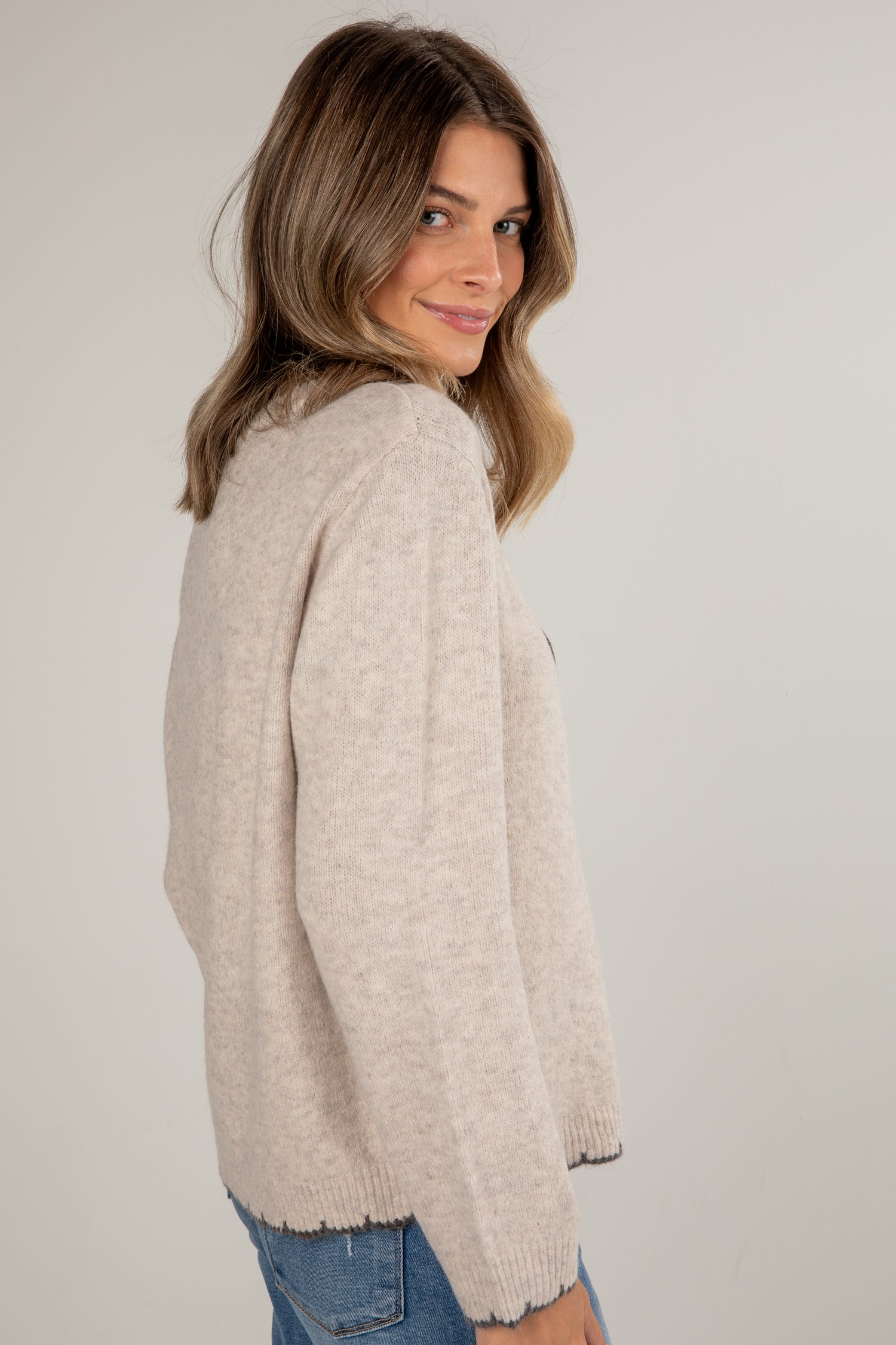 Woman wearing a beige sweater against a plain background
