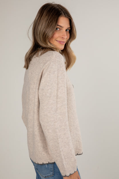 Woman wearing a beige sweater against a plain background