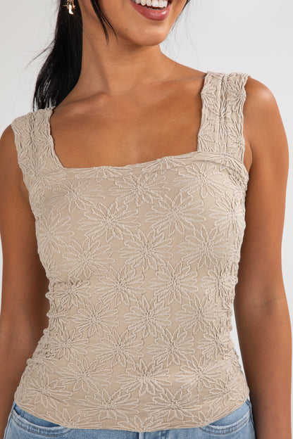 Woman wearing a beige lace top against a white background