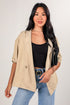 Woman wearing a beige jacket, black top, and blue jeans on a white background