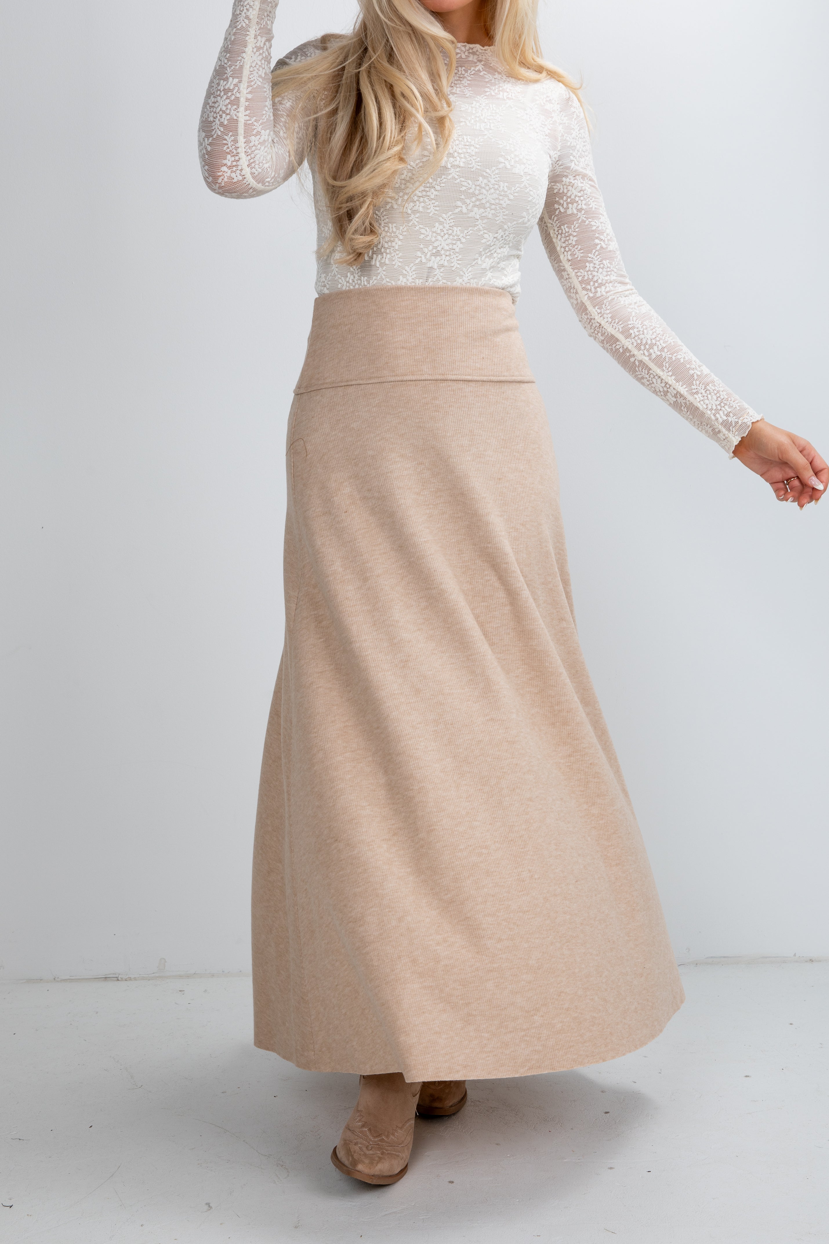 Woman wearing a beige skirt and white top on a plain background