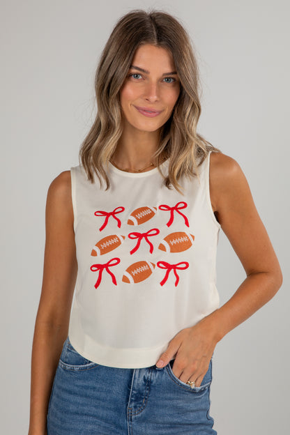 Woman wearing a sleeveless top with football and bow designs on a plain background
