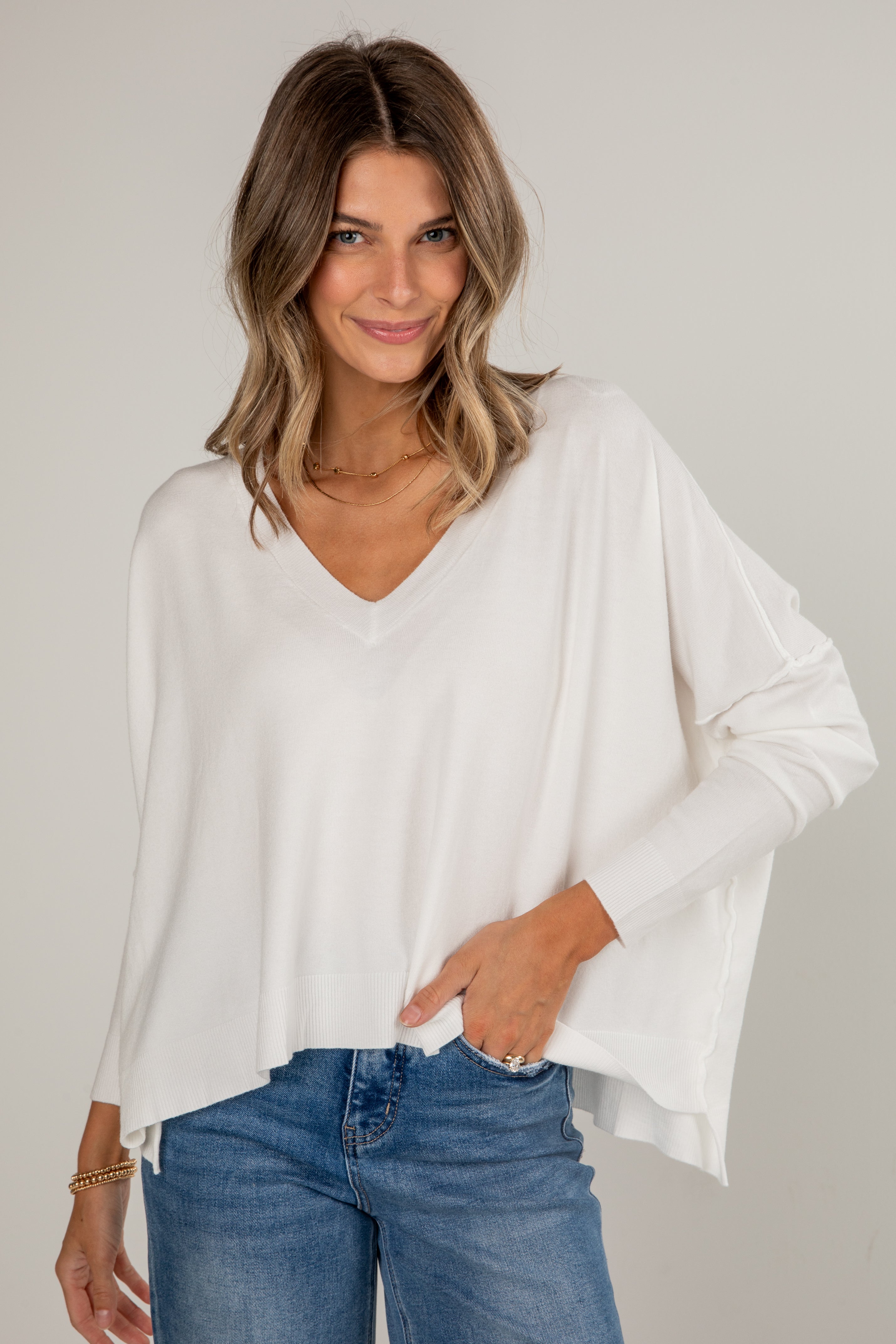 Woman wearing a white blouse and blue jeans against a plain background