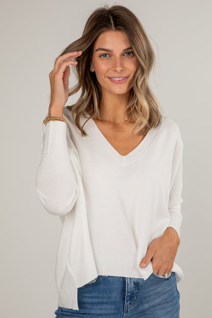 Woman wearing a white blouse and blue jeans against a plain background