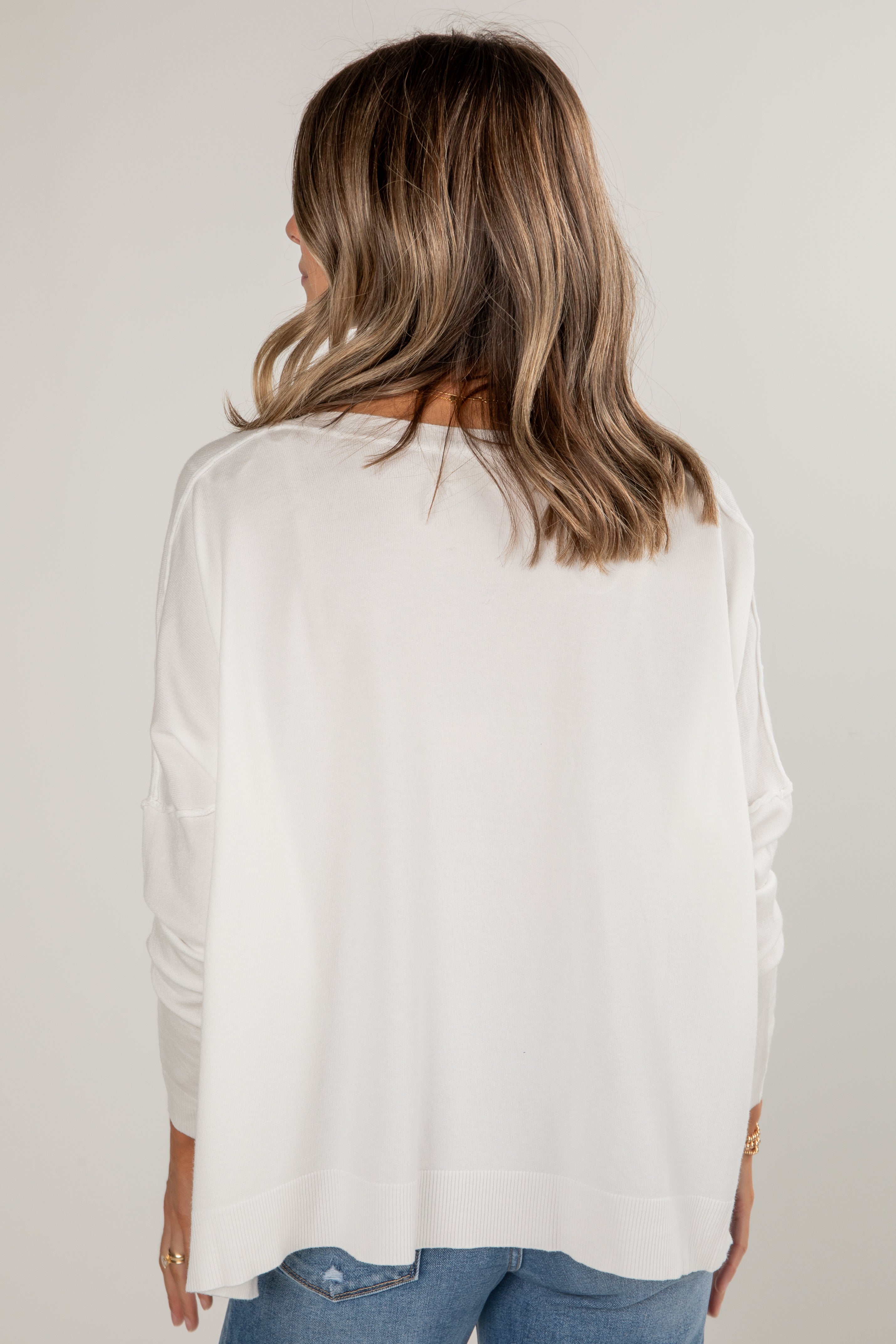 Person wearing a white blouse with long sleeves on a plain background