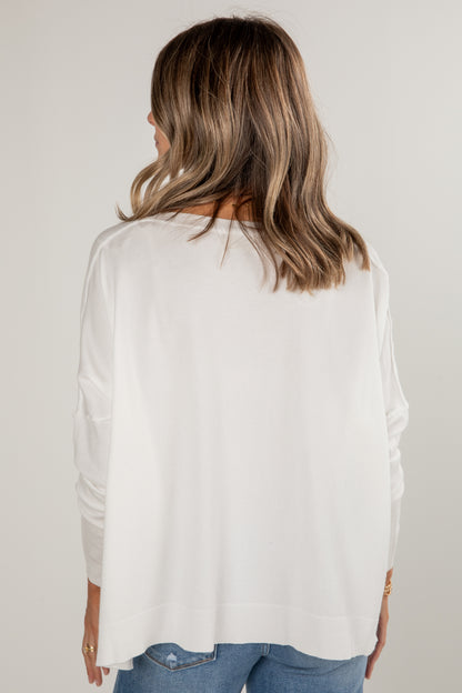Person wearing a white blouse with long sleeves on a plain background