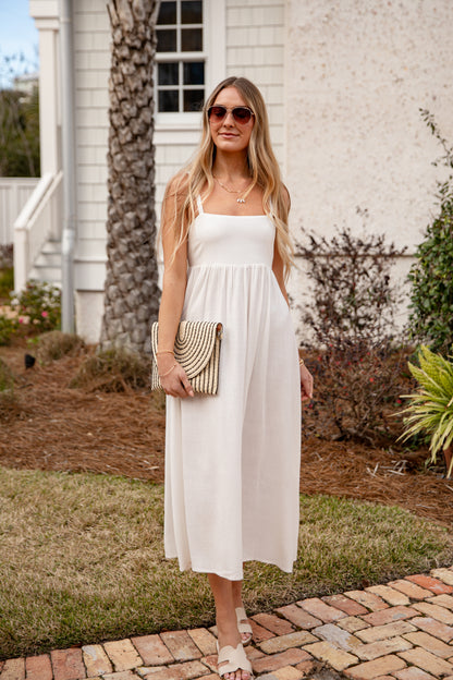 Woman in a white dress standing outdoors near a building