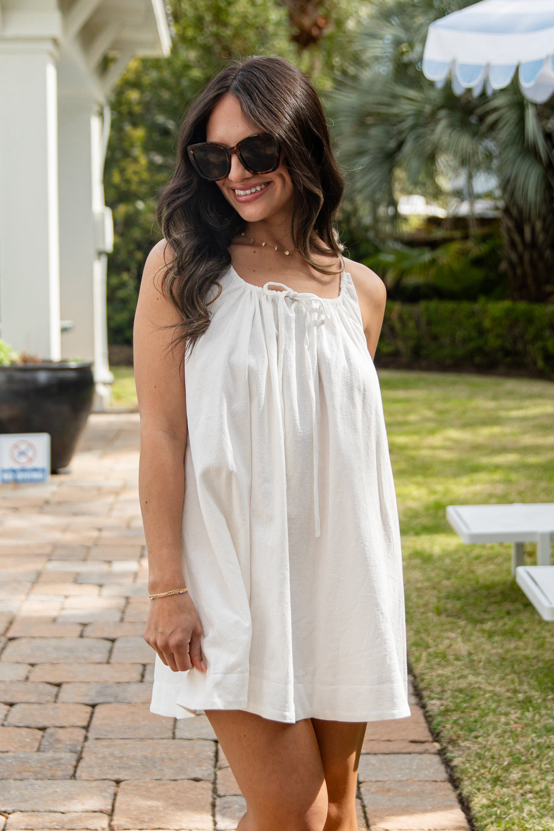 Woman in a white dress standing outdoors on a patio