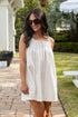 Woman in a white dress standing outdoors on a patio