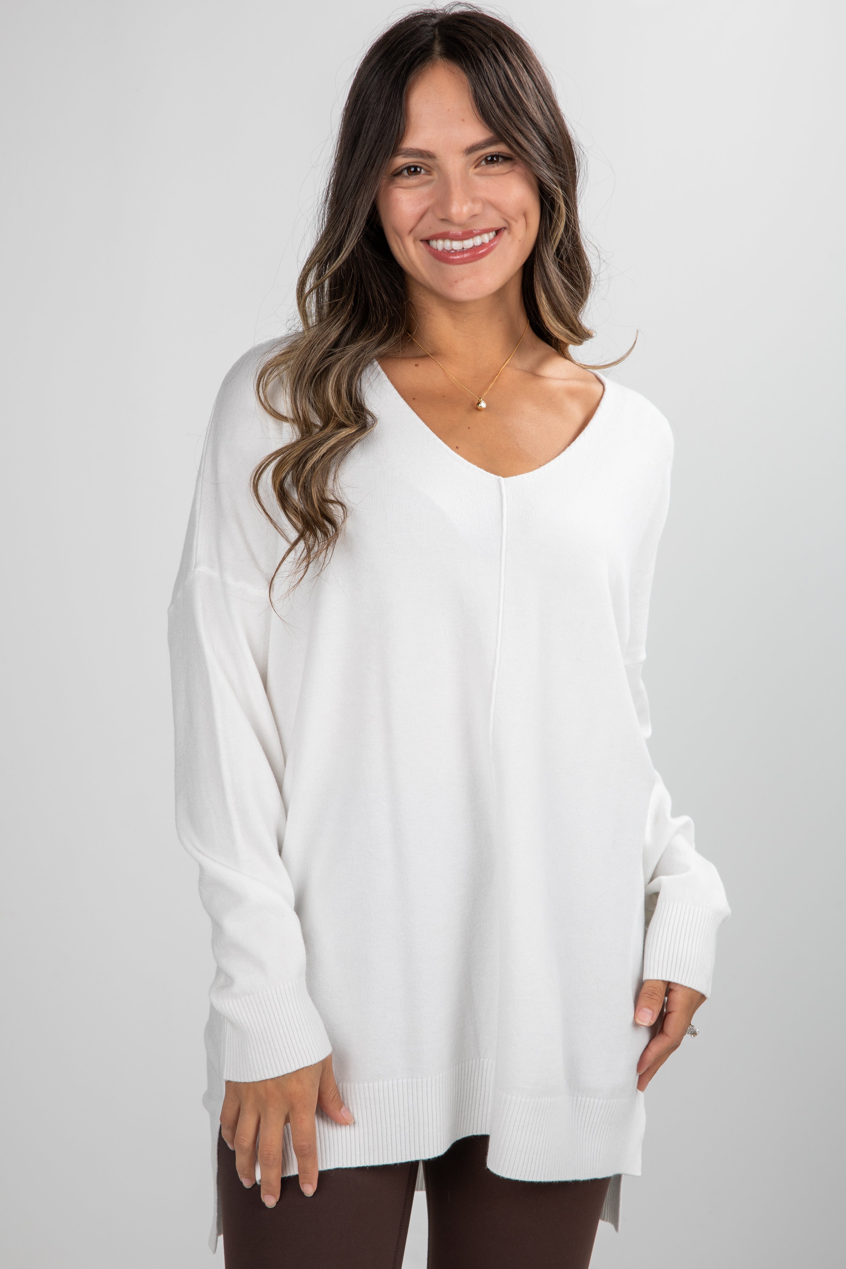 Woman wearing a white long-sleeve top against a plain background