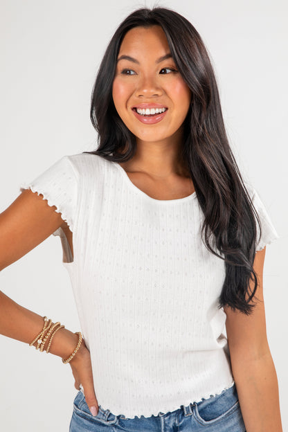 Woman wearing a white t-shirt with cut-out shoulders against a plain background