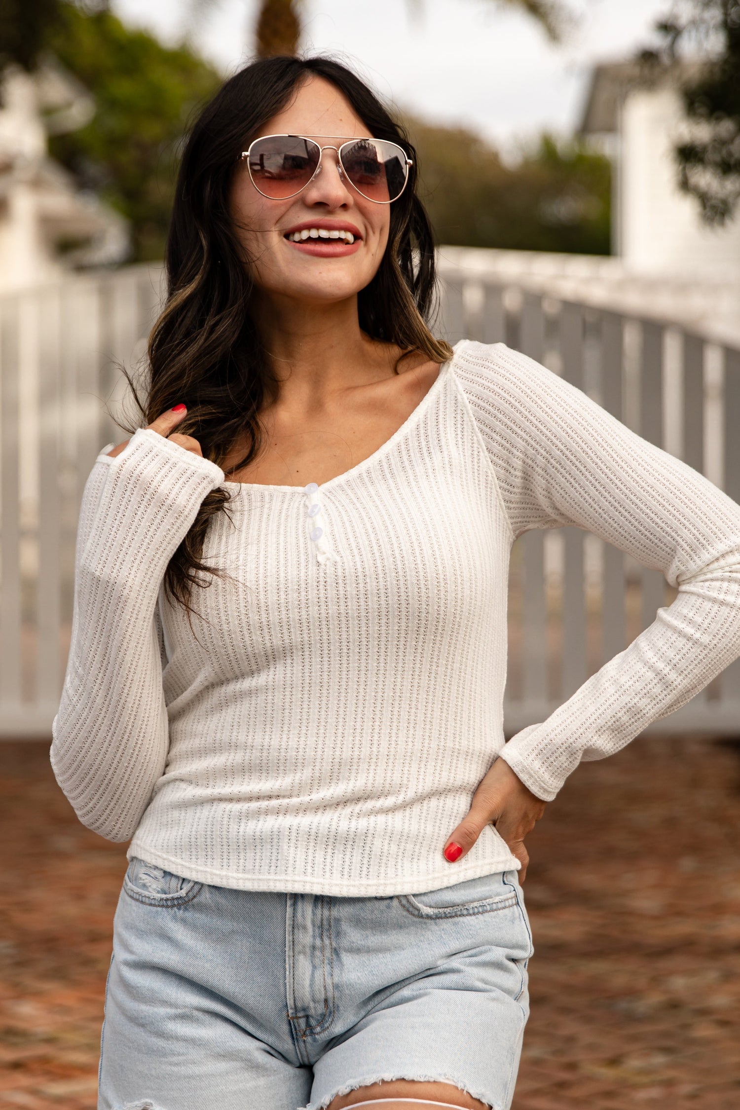 Woman wearing a white sweater and denim shorts outdoors
