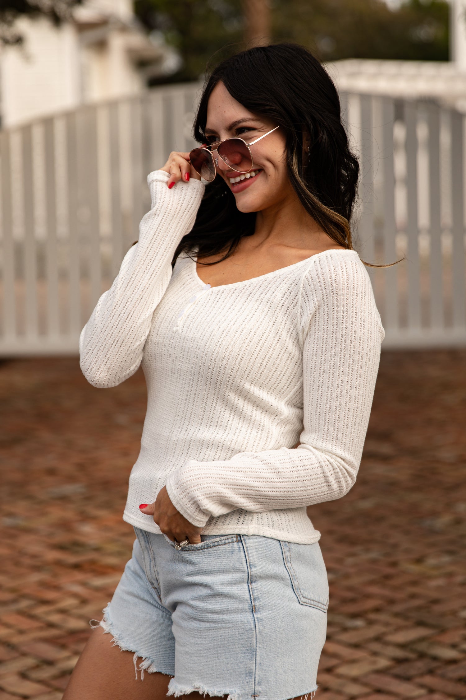 Woman wearing a white sweater and denim shorts outdoors