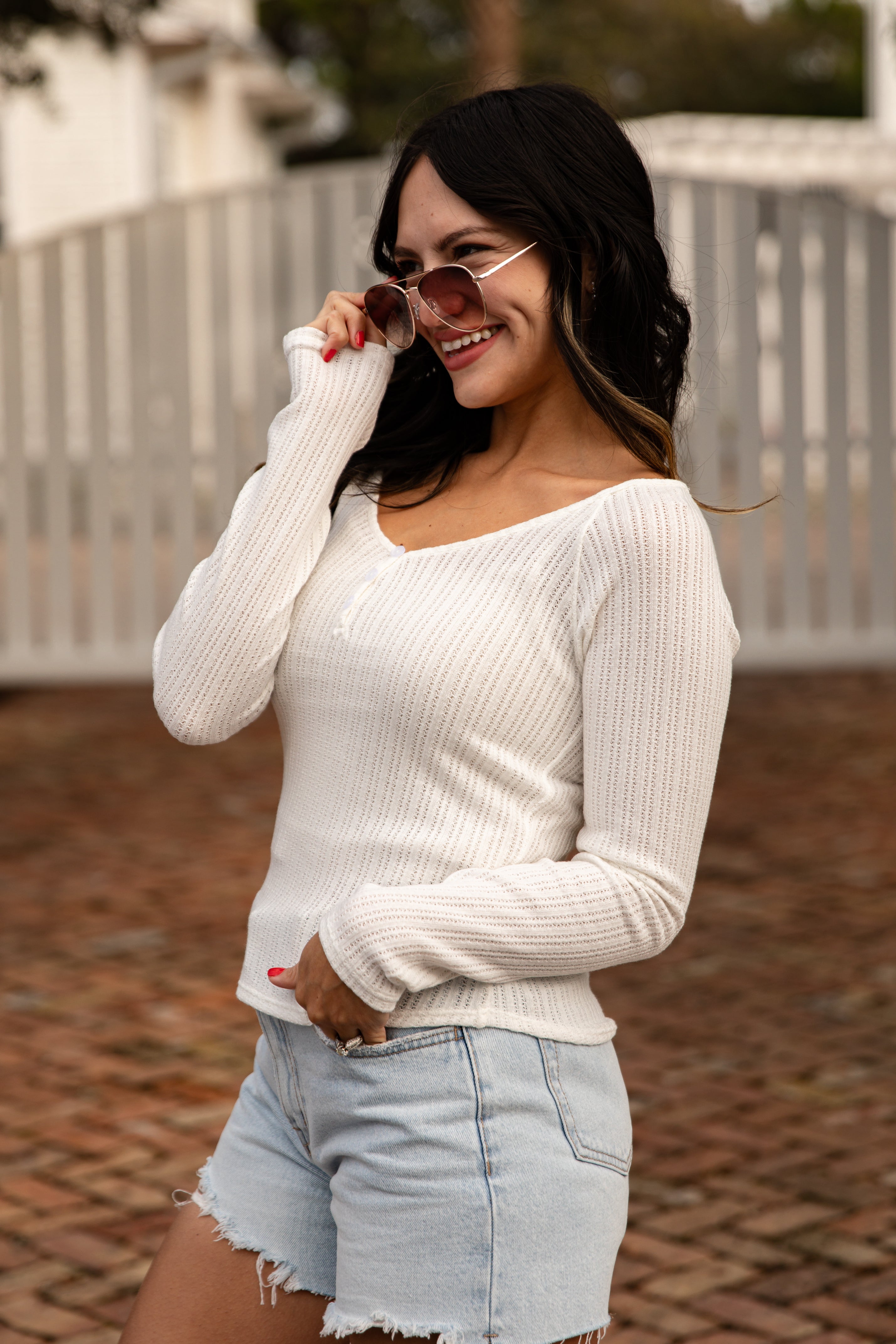 Woman wearing a white sweater and denim shorts outdoors