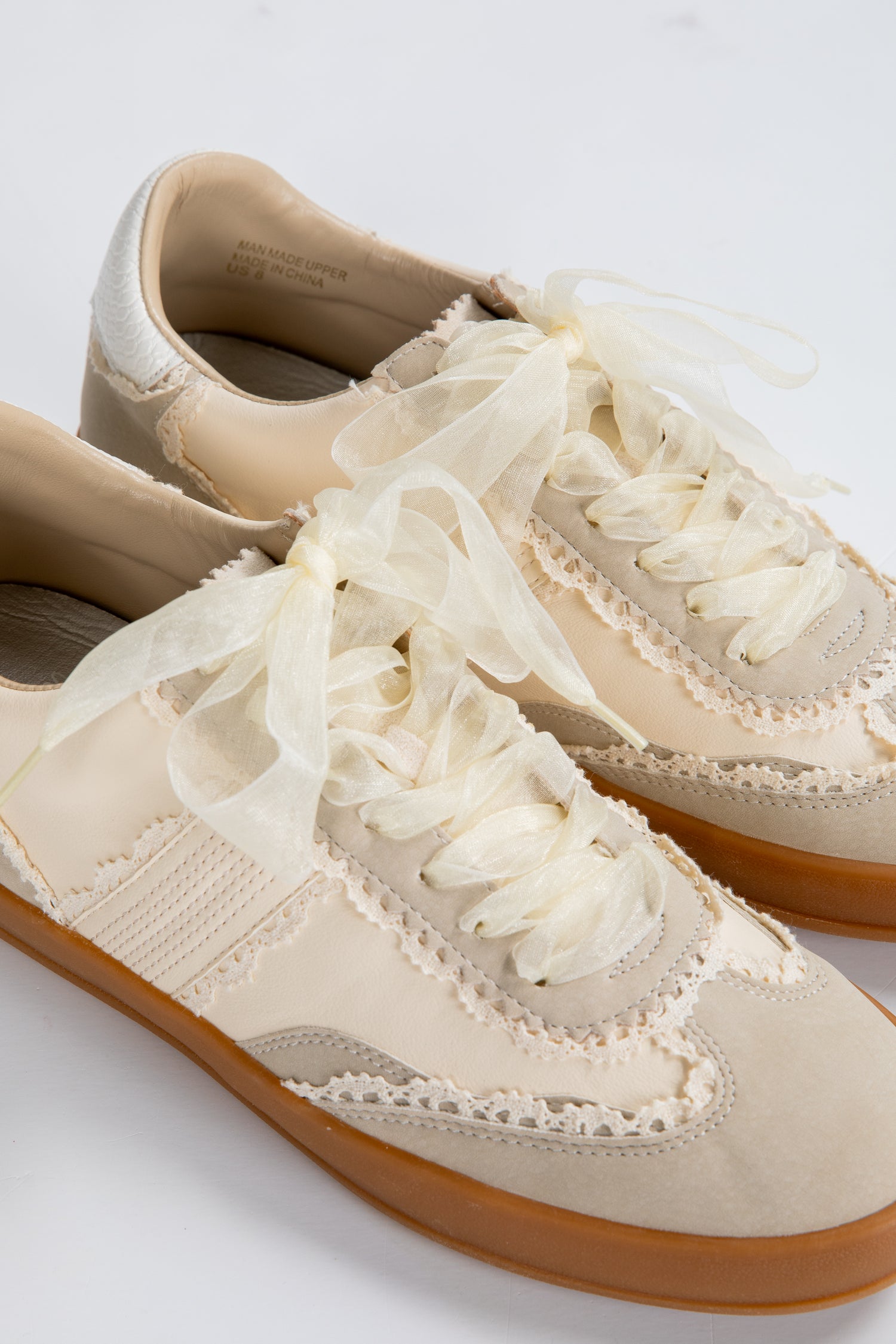 Beige sneakers with white laces on a light gray background