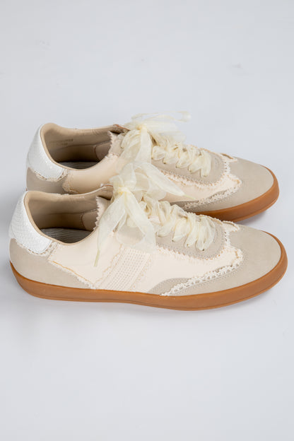 Pair of cream-colored sneakers with brown soles on a light gray background