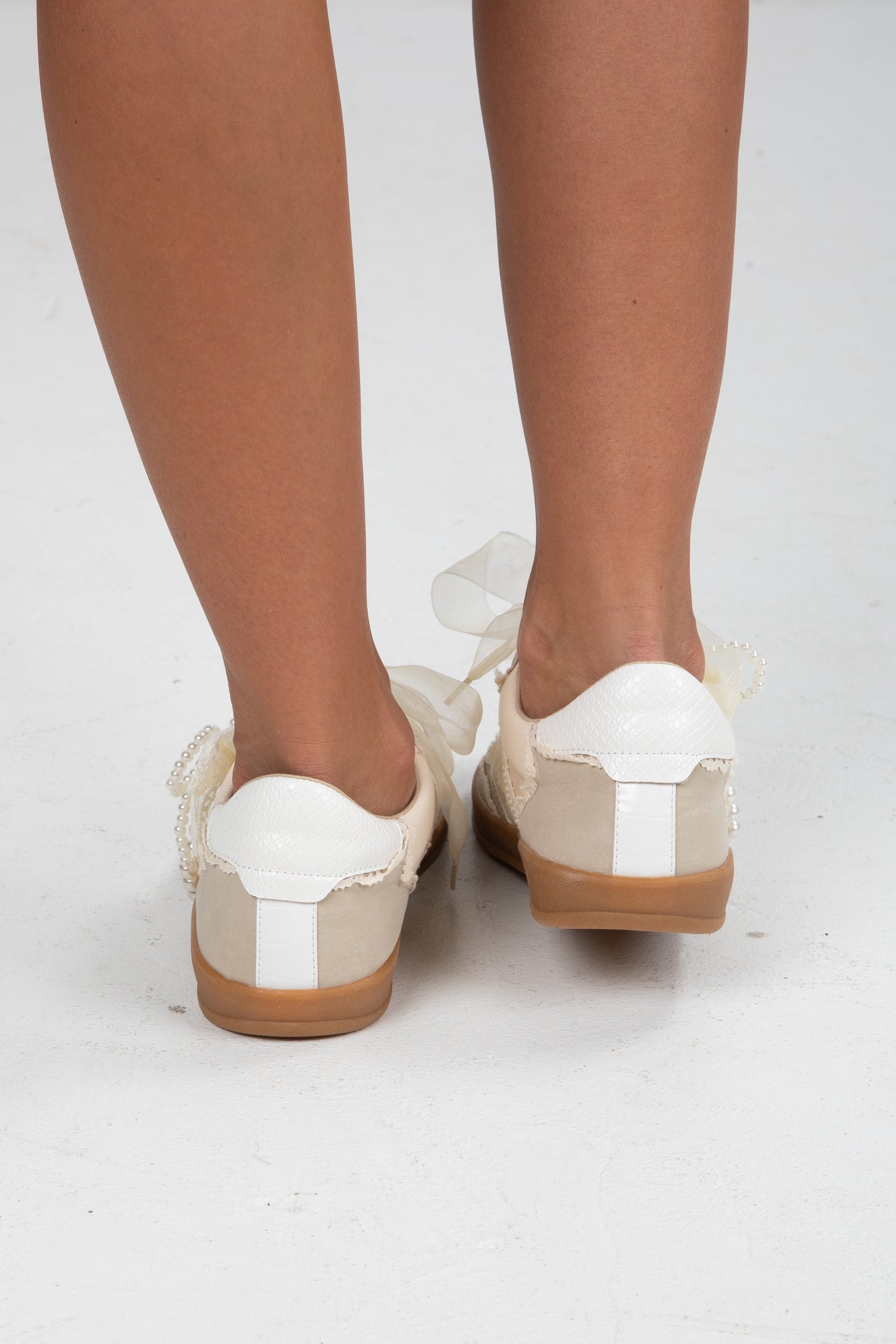 White and brown shoes worn by a person on a white background