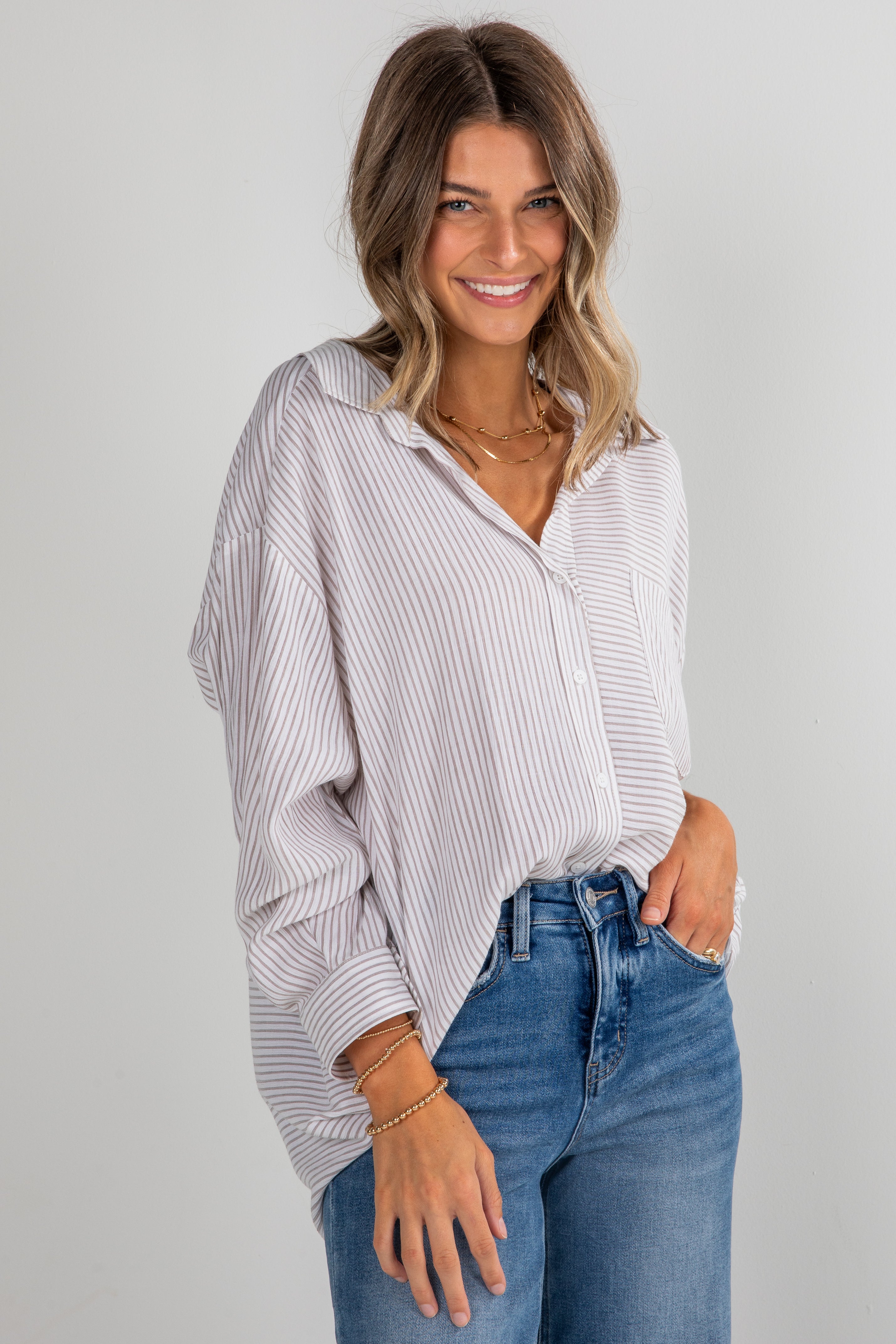 Woman wearing a striped shirt and jeans on a plain background