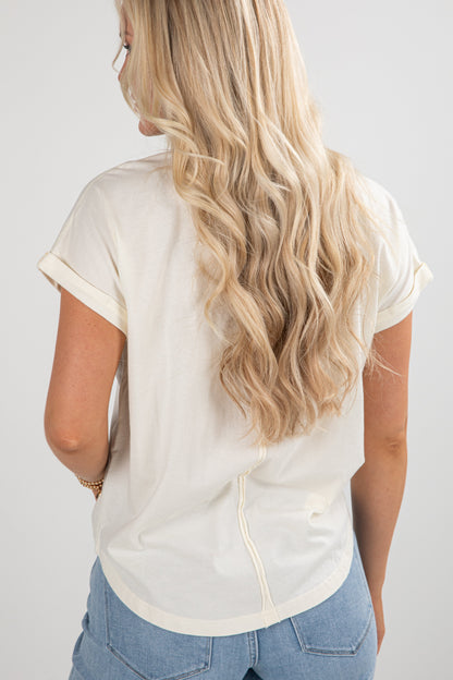 Person wearing a white blouse with short sleeves and blue jeans on a plain background