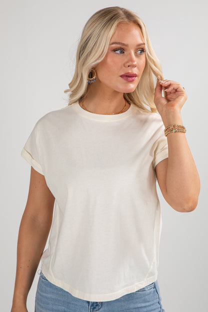 Woman wearing a white t-shirt and blue jeans against a plain background