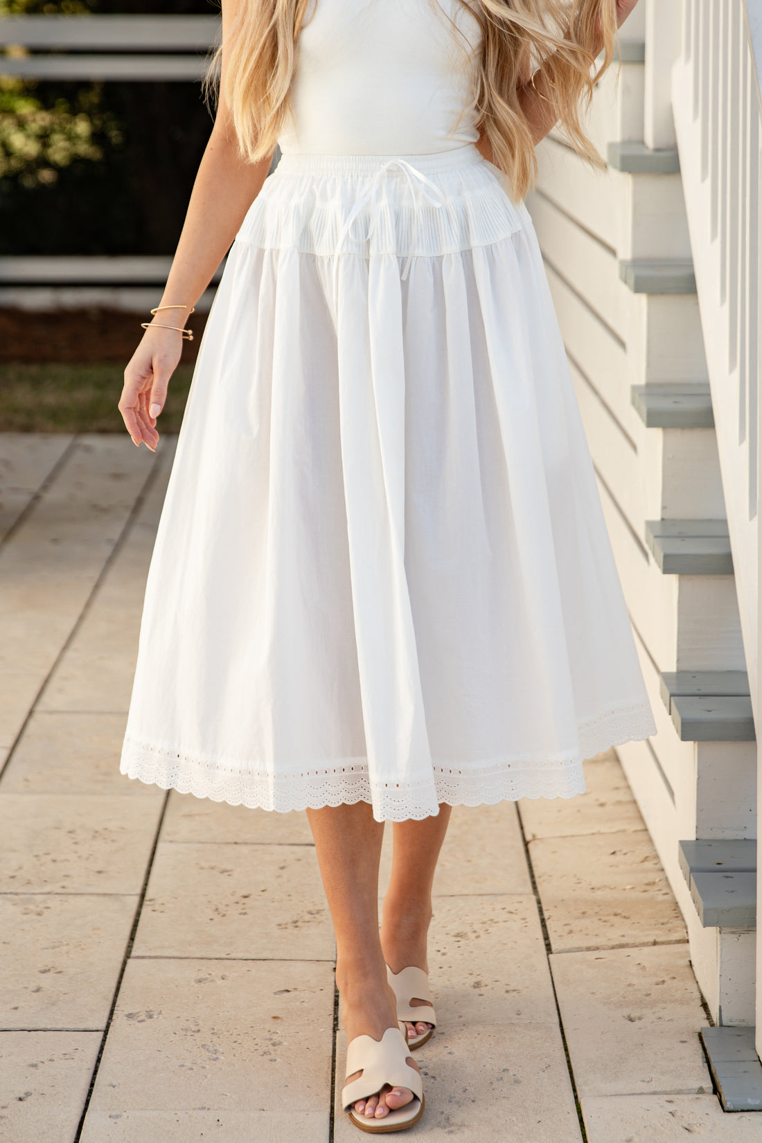 Woman wearing a white skirt standing on a wooden deck.