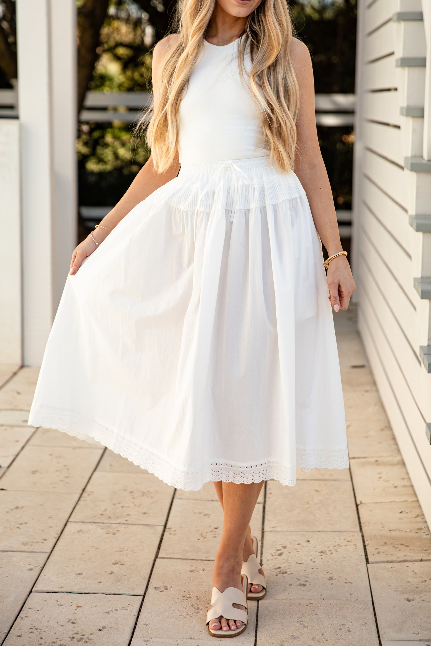 Woman wearing a white skirt standing on a wooden deck.