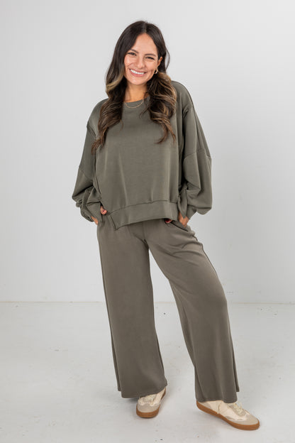 Woman wearing an olive green outfit with a matching top and pants on a white background