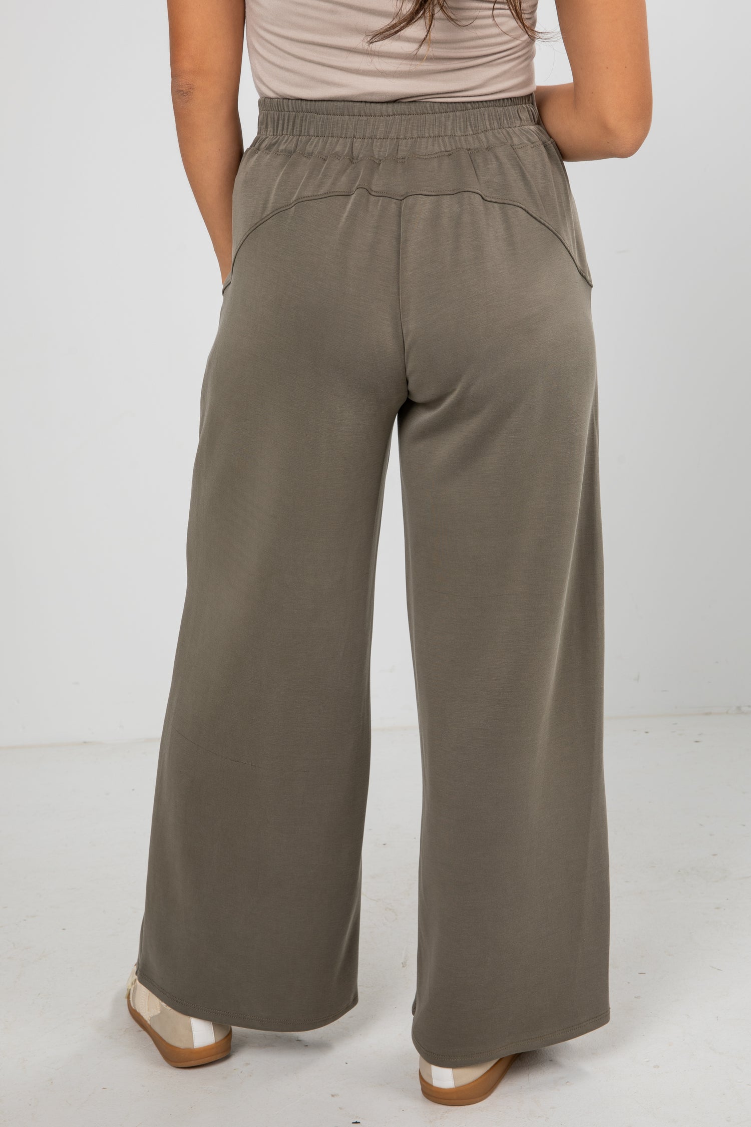Person wearing olive green wide-leg pants on a white background