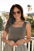Woman wearing sunglasses and a sleeveless top with a blurred outdoor background
