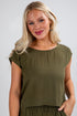 Woman wearing an olive green top against a plain background