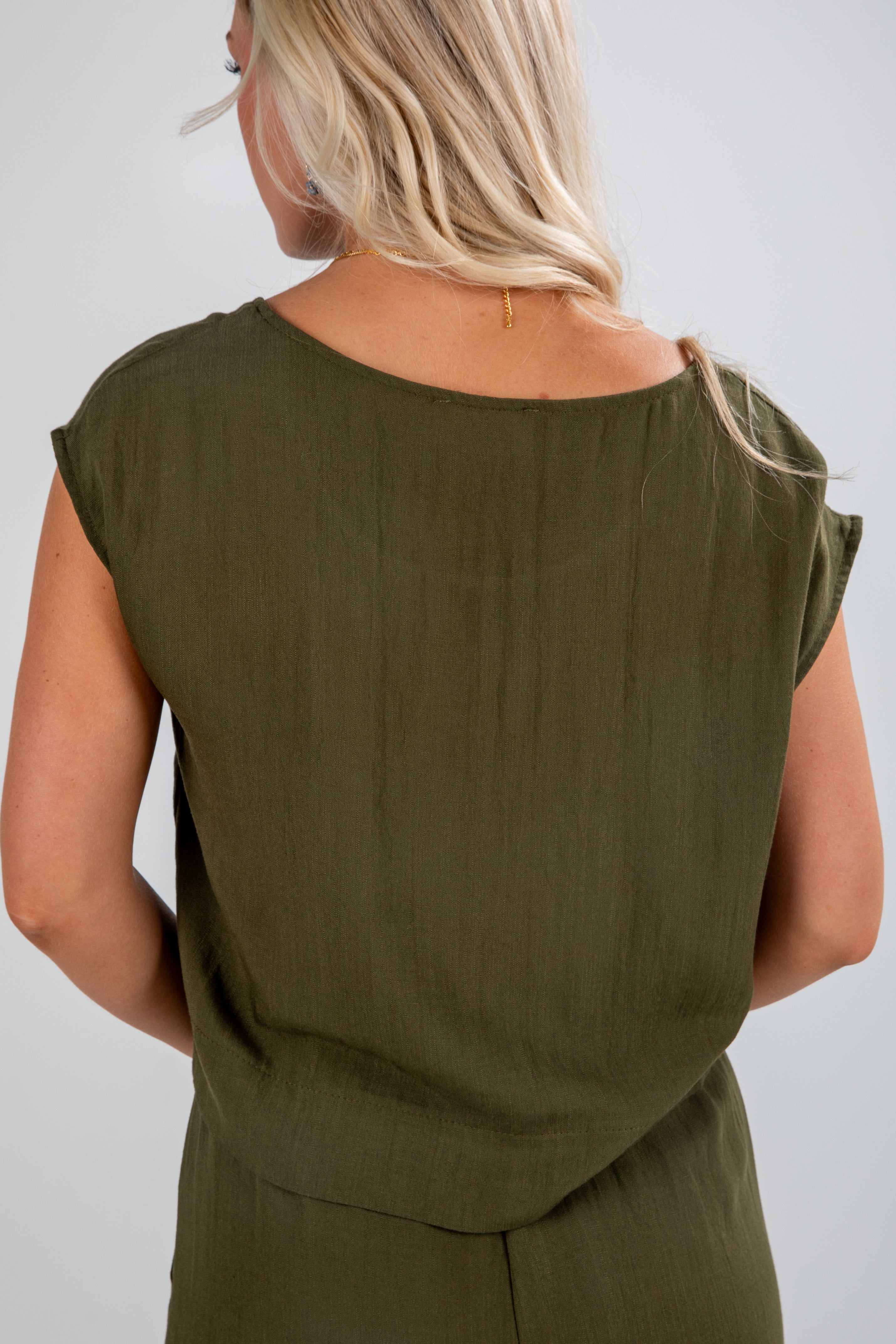 Person wearing an olive green sleeveless top against a plain background