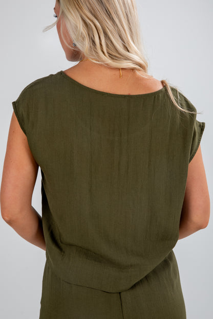 Person wearing an olive green sleeveless top against a plain background