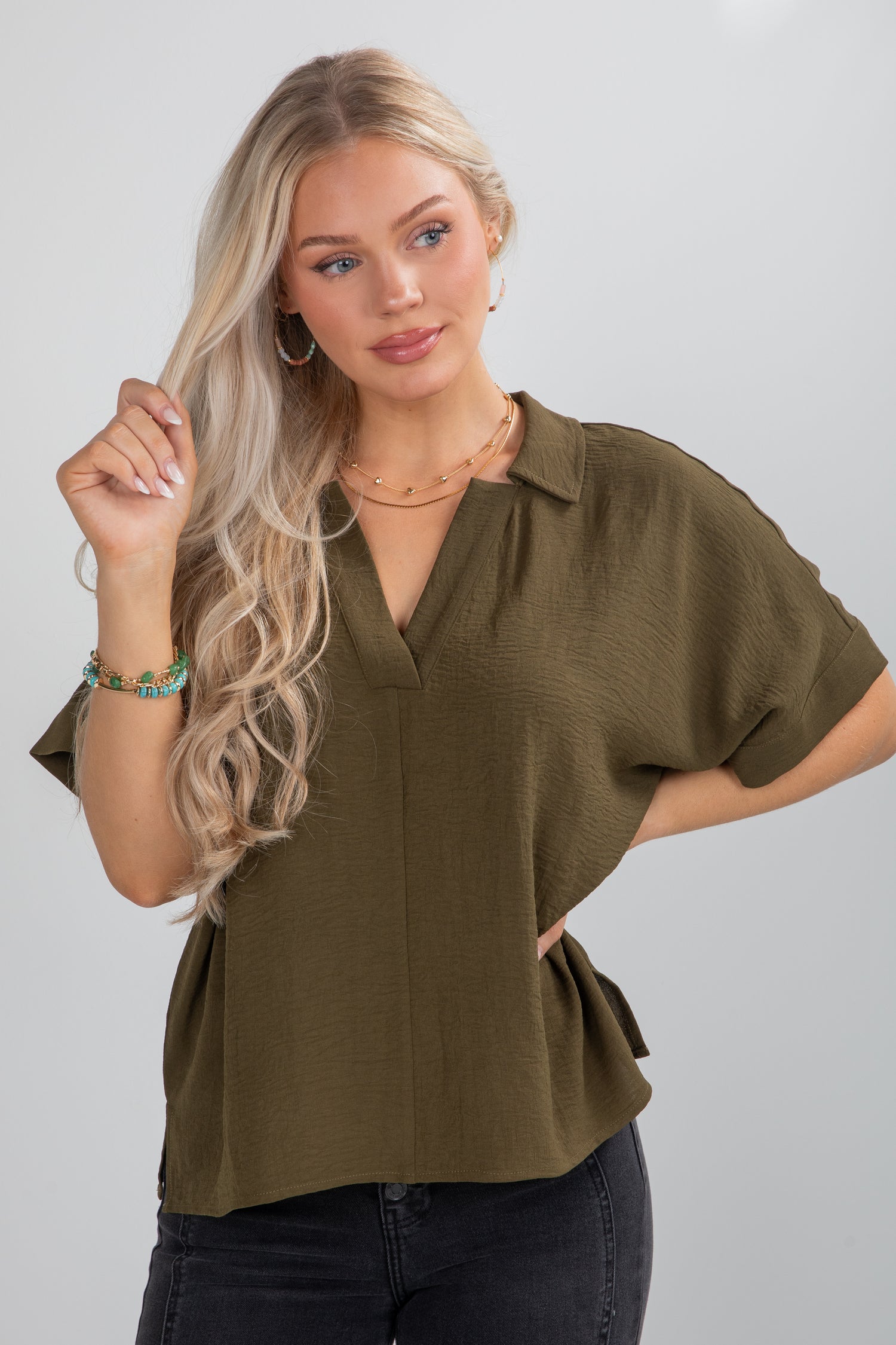 Woman wearing an olive green blouse against a plain background