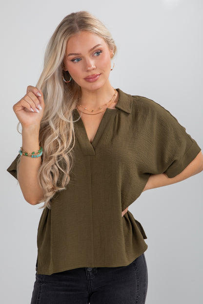 Woman wearing an olive green blouse against a plain background