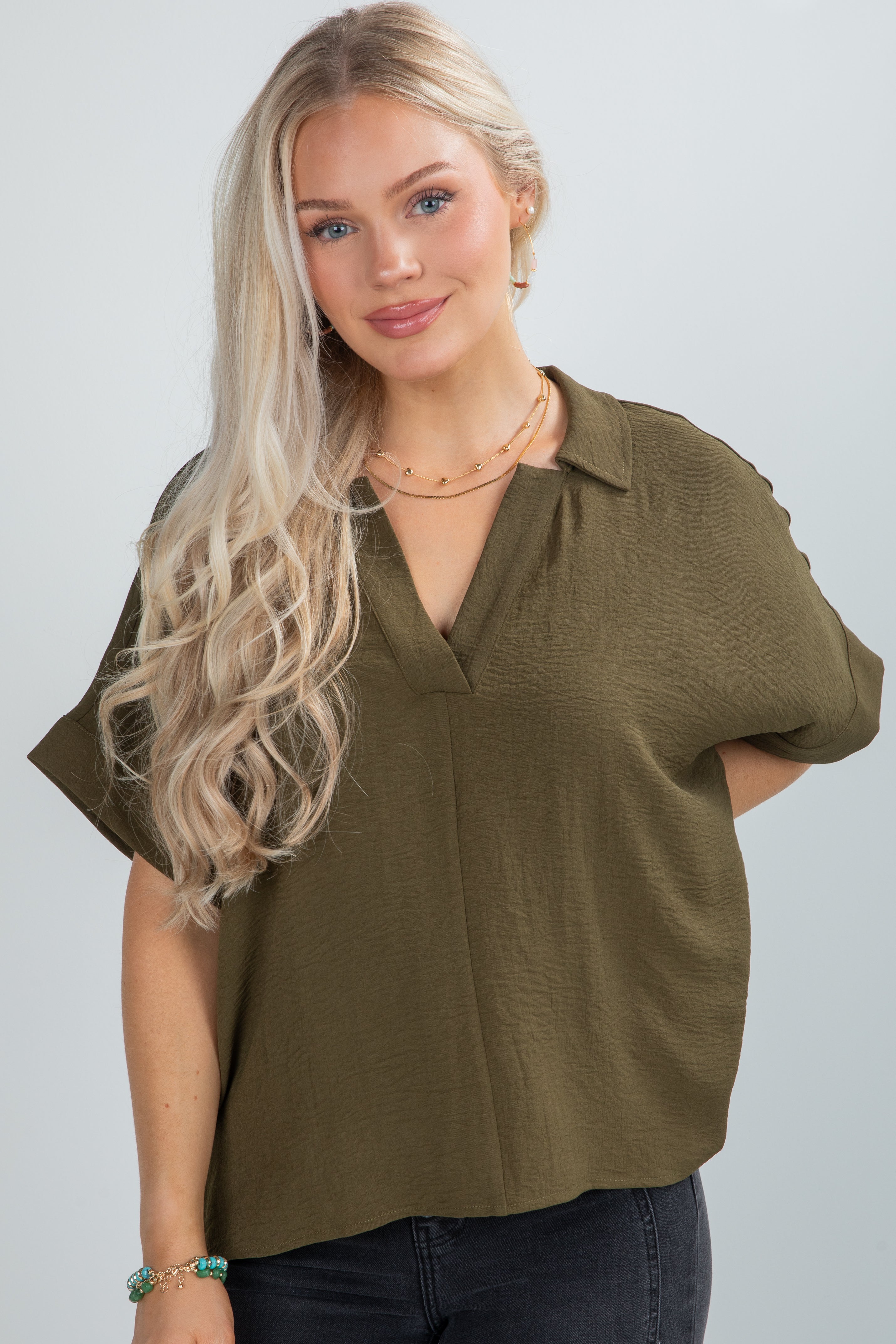 Woman wearing an olive green blouse against a plain background