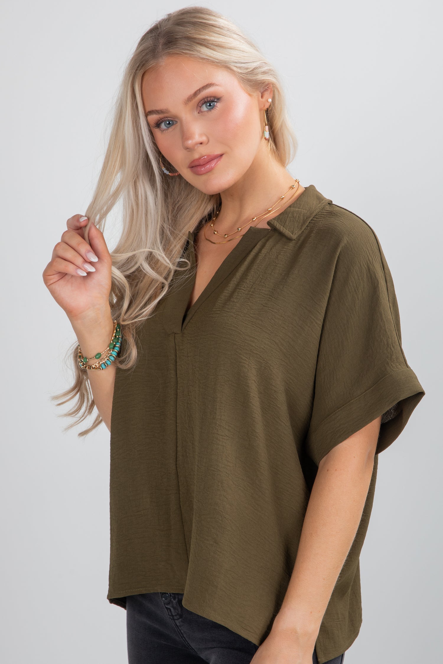 Woman wearing an olive green blouse against a plain background