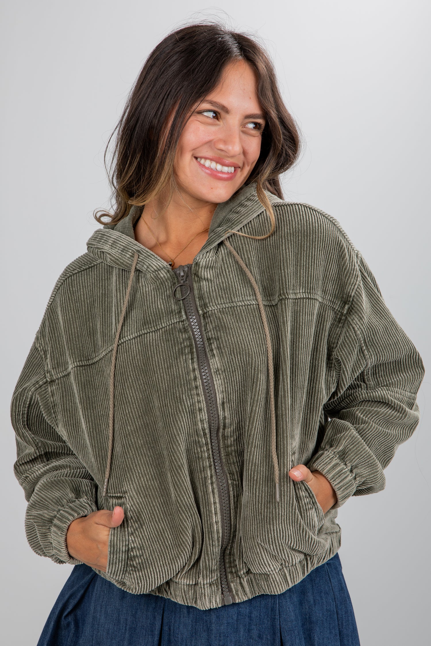 Woman wearing a green corduroy jacket against a plain background