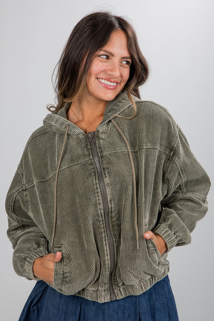 Woman wearing a green corduroy jacket against a plain background